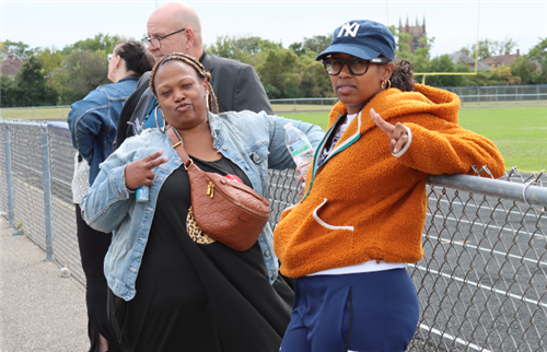 2 women smiling and standing by the fence
